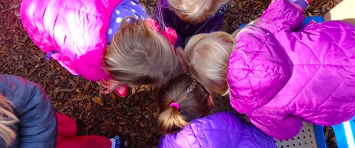 Children in colorful coats huddled together, viewed from above