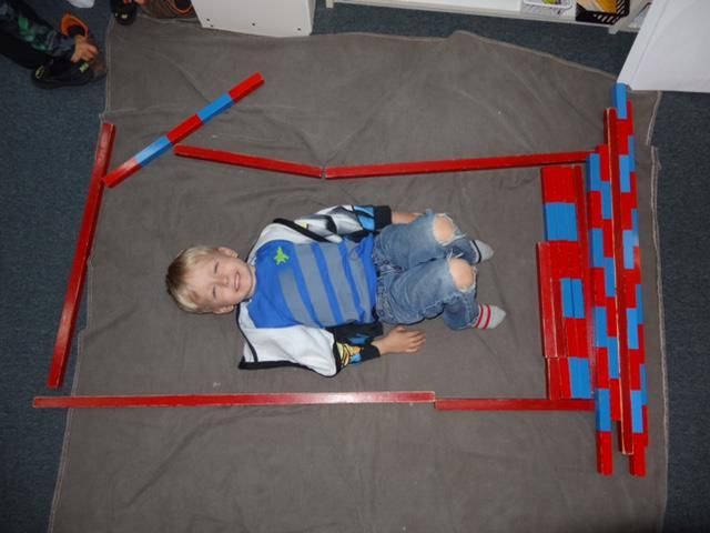 Boy lies on a gray blanket inside a red frame