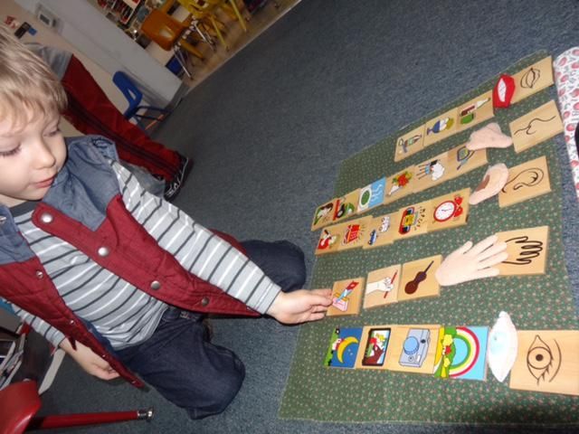 A young boy playing with wooden matching blocks on a carpet
