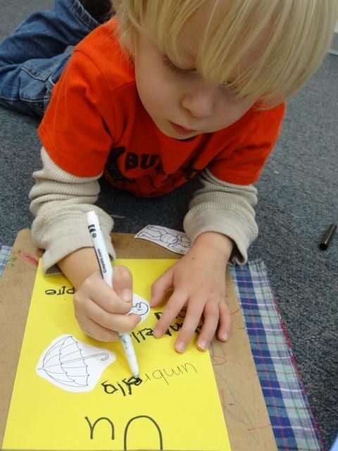 Blonde boy writing the word 