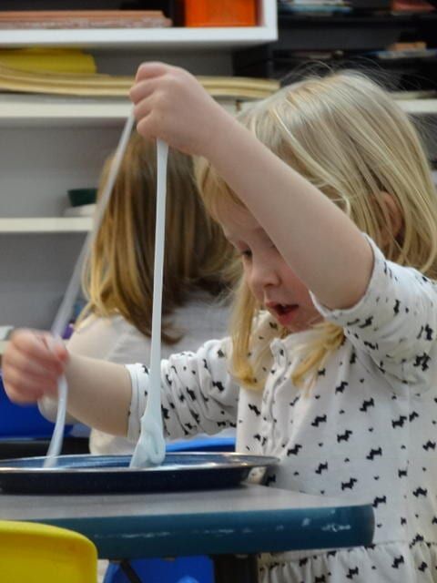 Blonde girl pulls up a long string of blue slime 