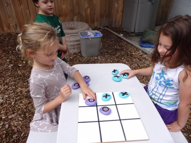Two girls playing tic-tac-toe outdoors