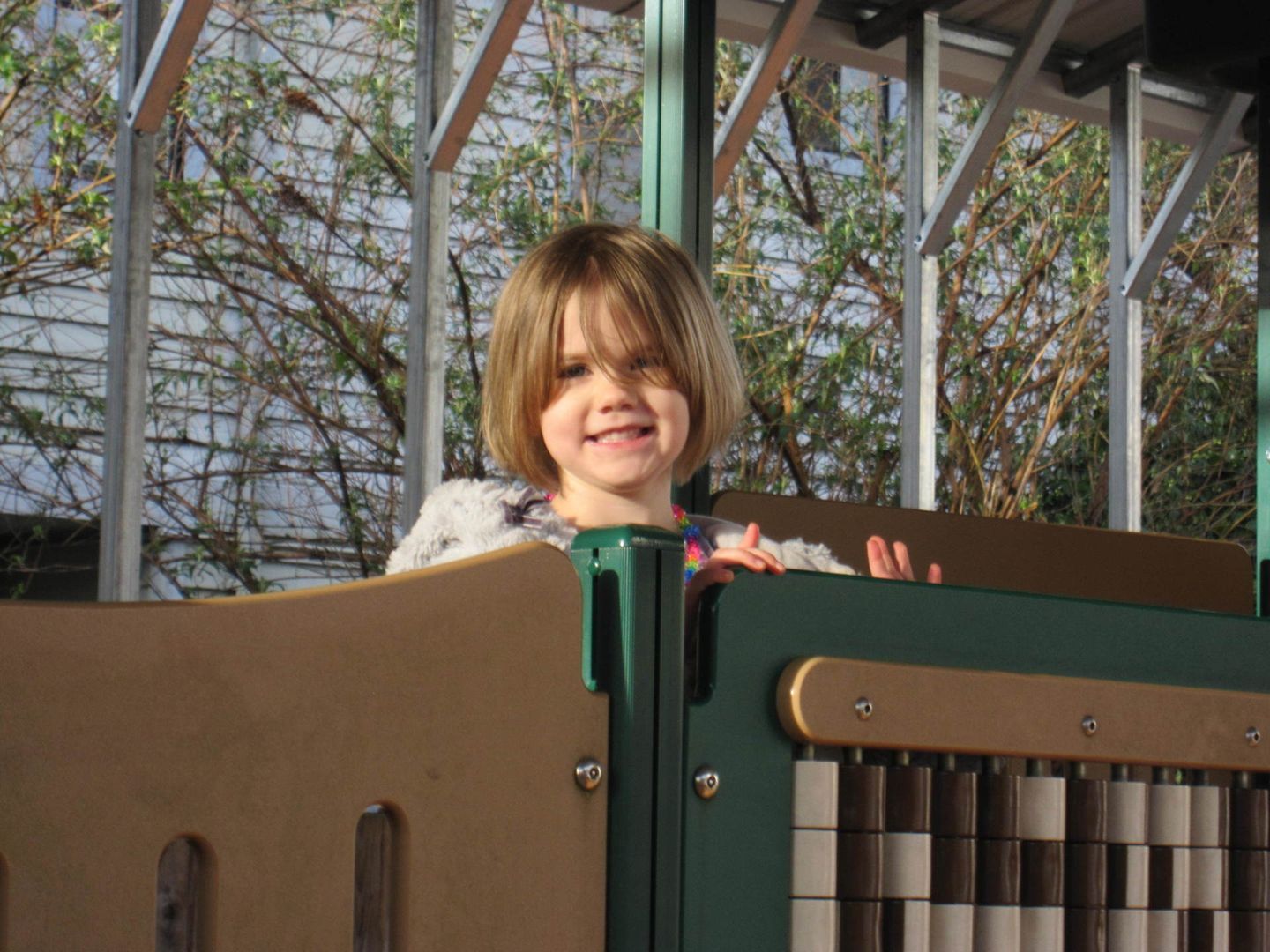 Smiling child peeking over a colorful playground structure