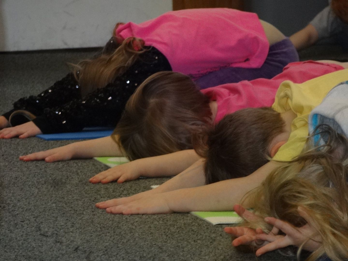 Children in various colorful shirts in a yoga pose