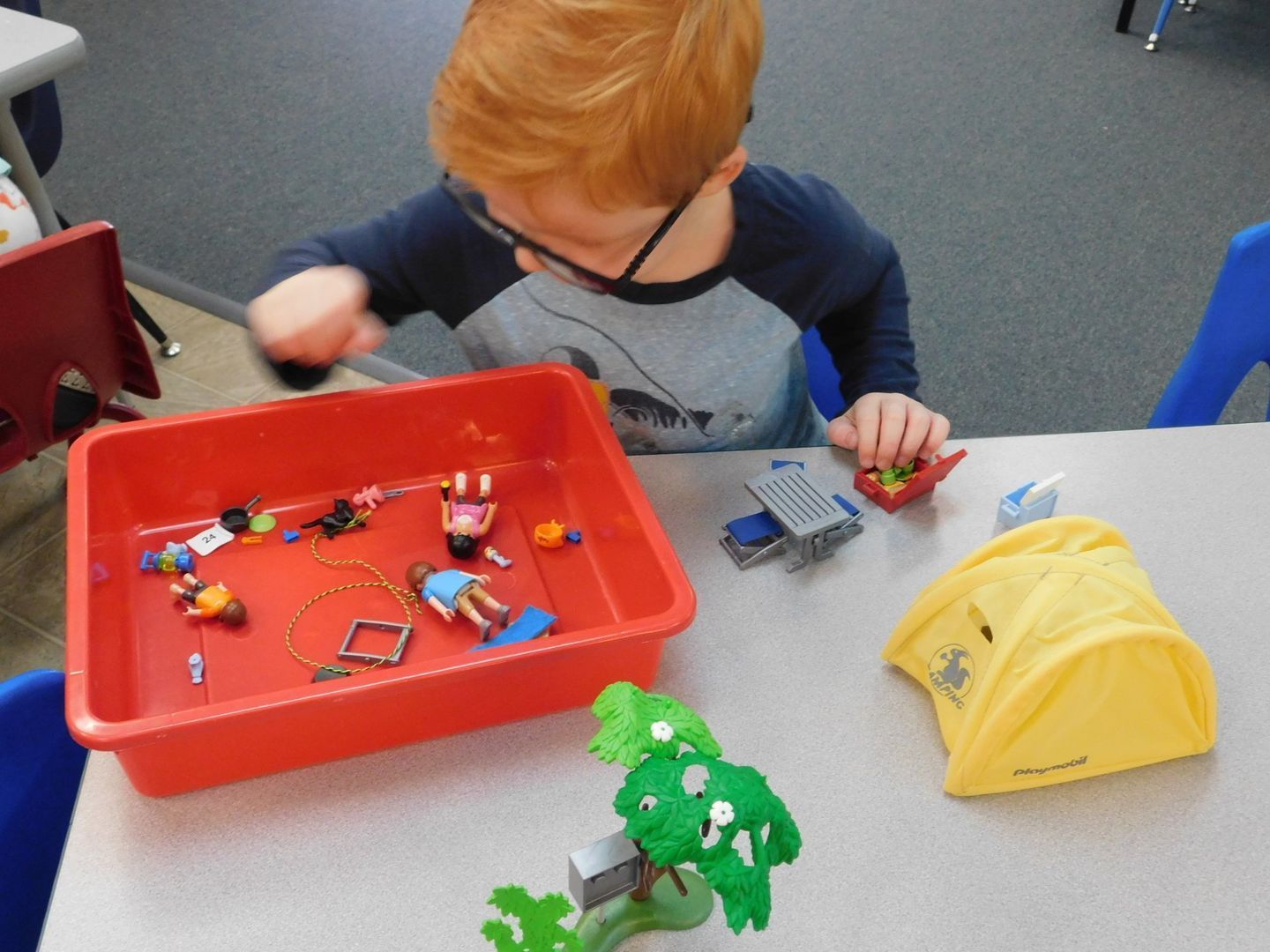 Boy with red hair playing with toys at a table