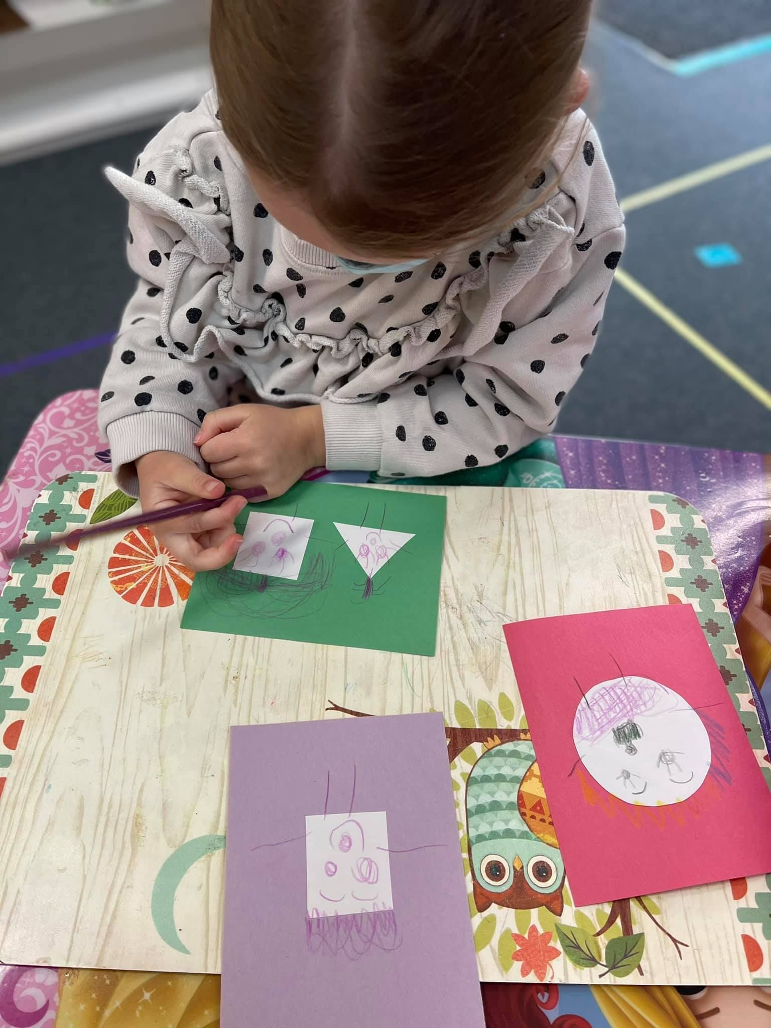 Child drawing on paper with shapes
