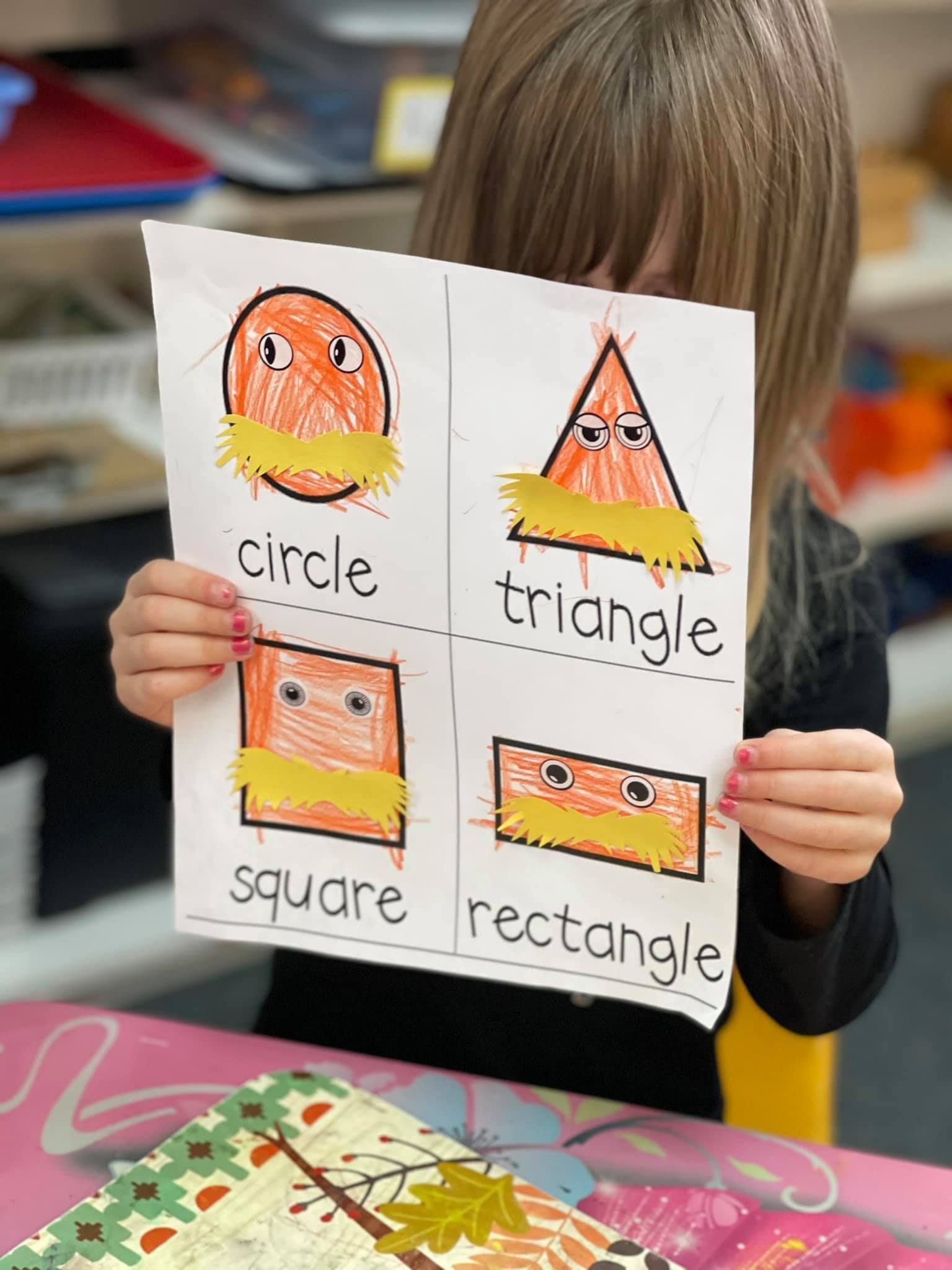 Girl holding a paper with drawn shapes