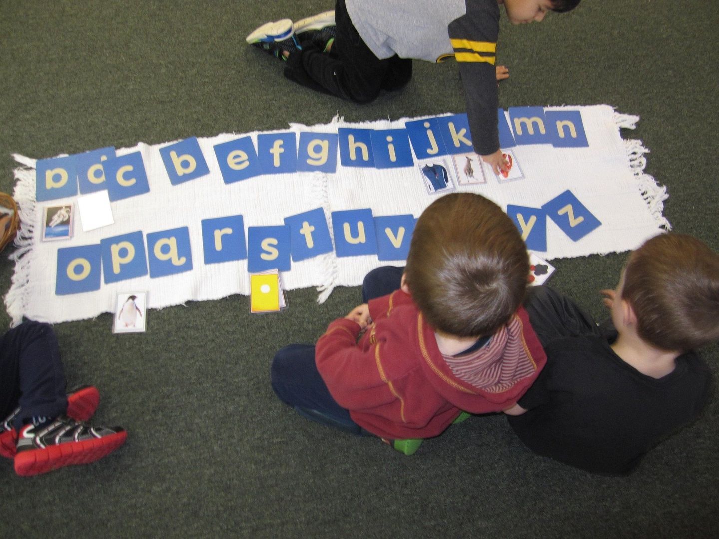 Children seated on floor with alphabet cards