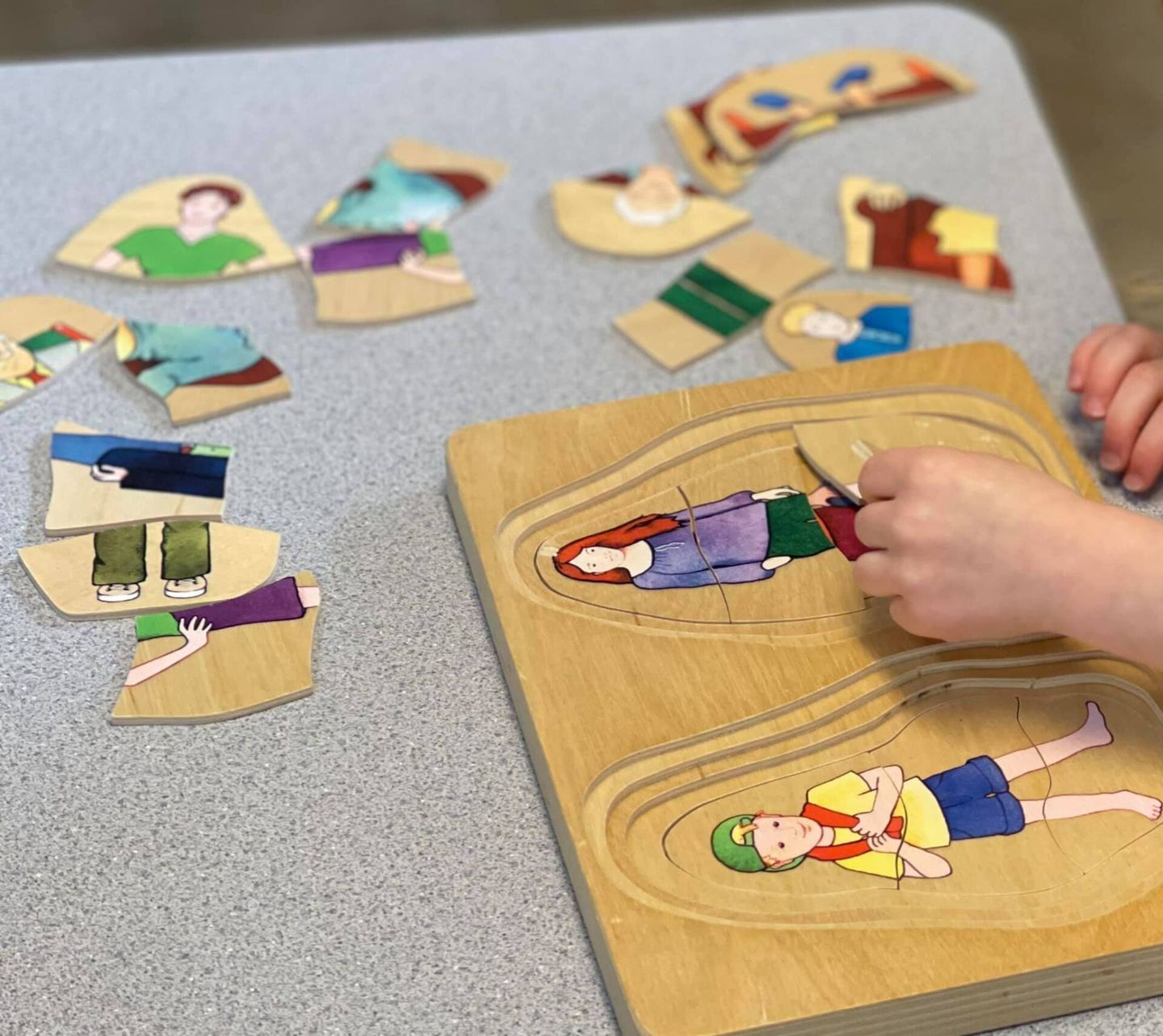 Child playing with a wooden puzzle of people