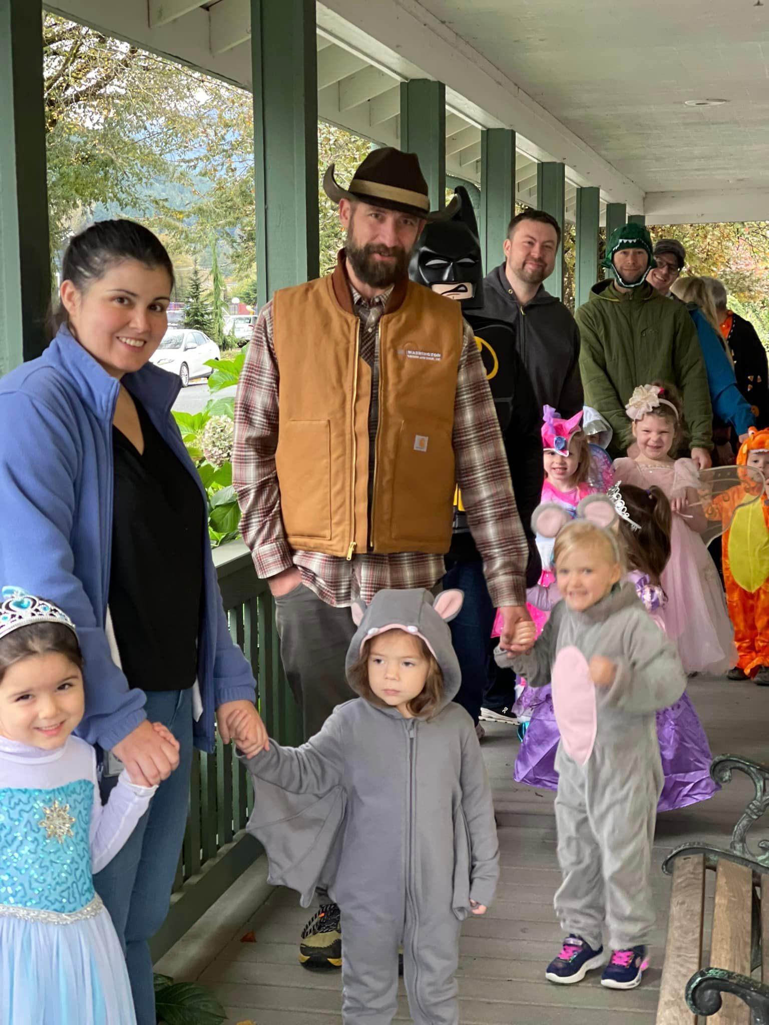 People in Halloween costumes and casual clothes stand on a porch
