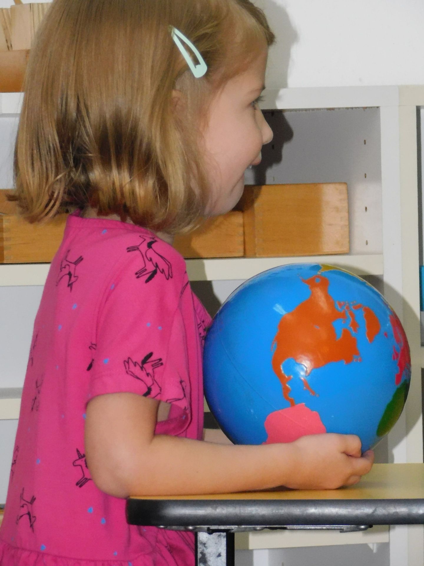Girl in pink shirt holding a blue globe
