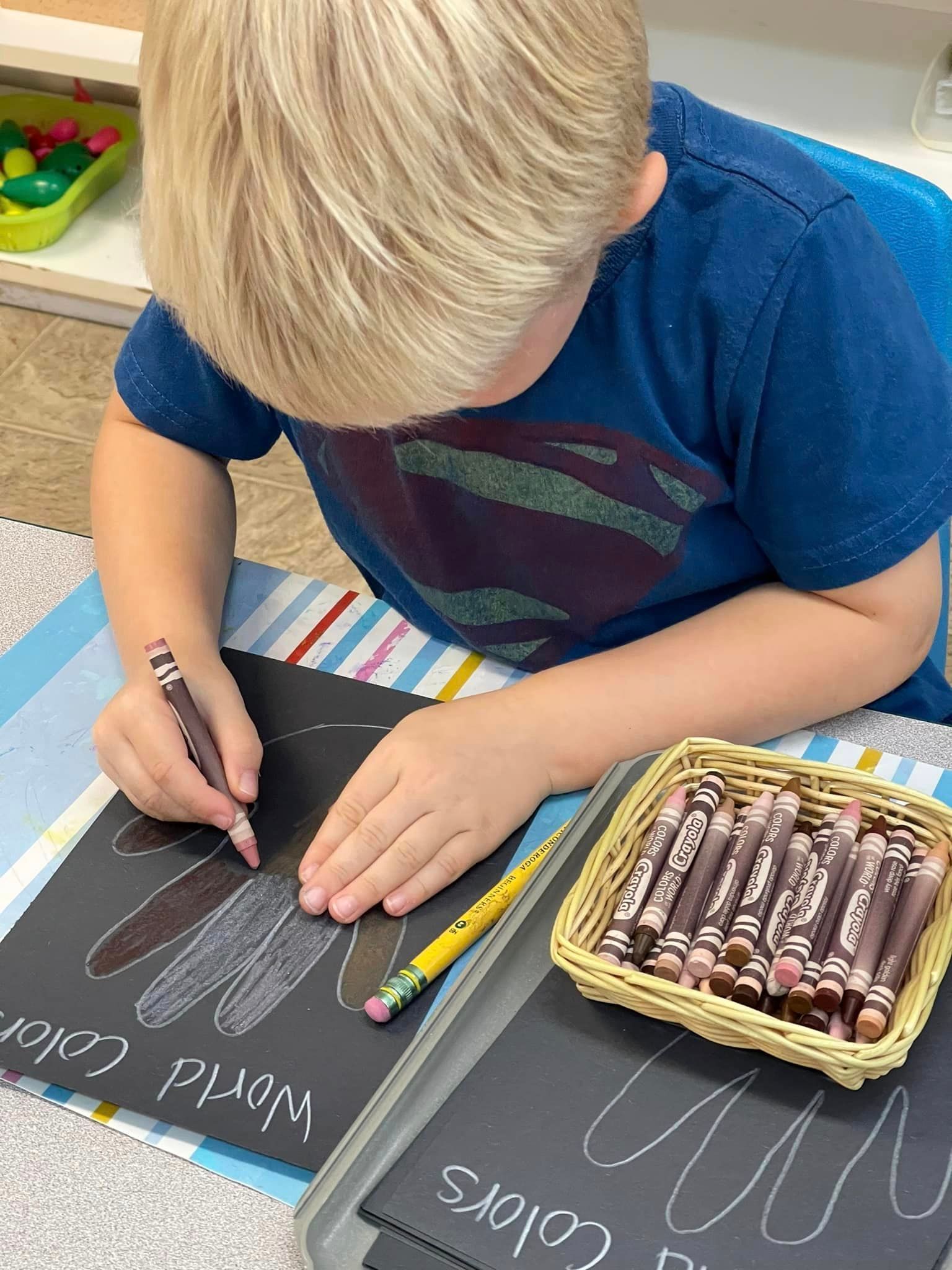 Blond child drawing on black paper