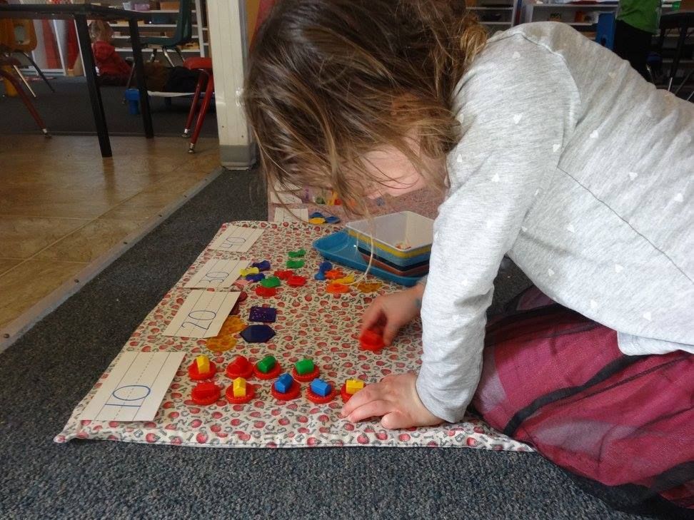 Young child sorting colorful shapes on a patterned mat indoors