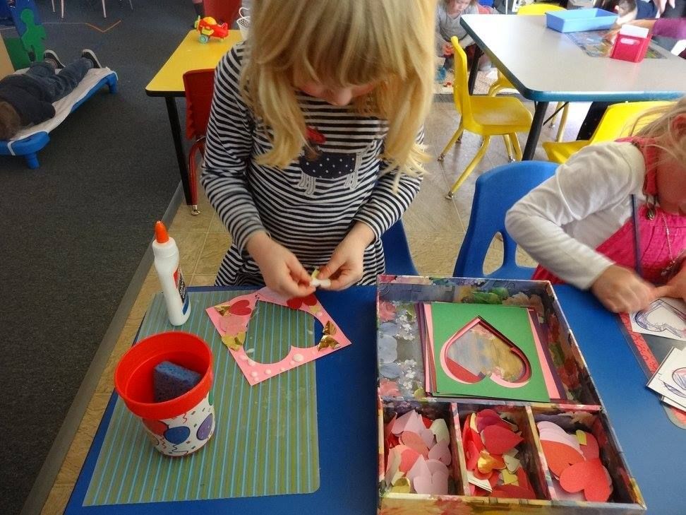 A young girl making art with heart cutouts