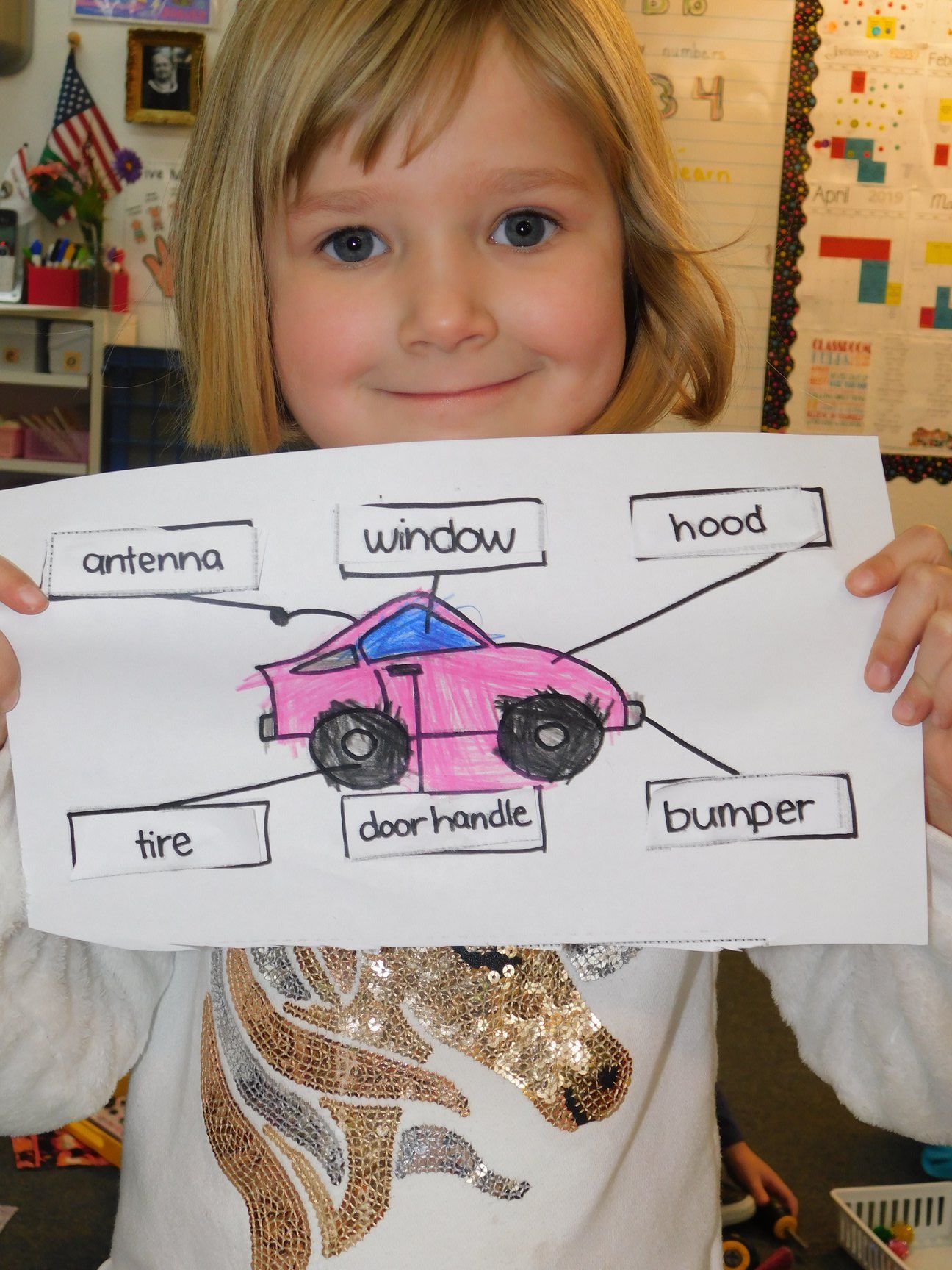 Girl holding a drawing of a pink car