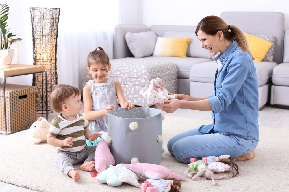 A Woman Is Sitting on The Floor with Two Children Playing with Stuffed Animals - Healthy Cleaning Solutions in Scotts Head, NSW