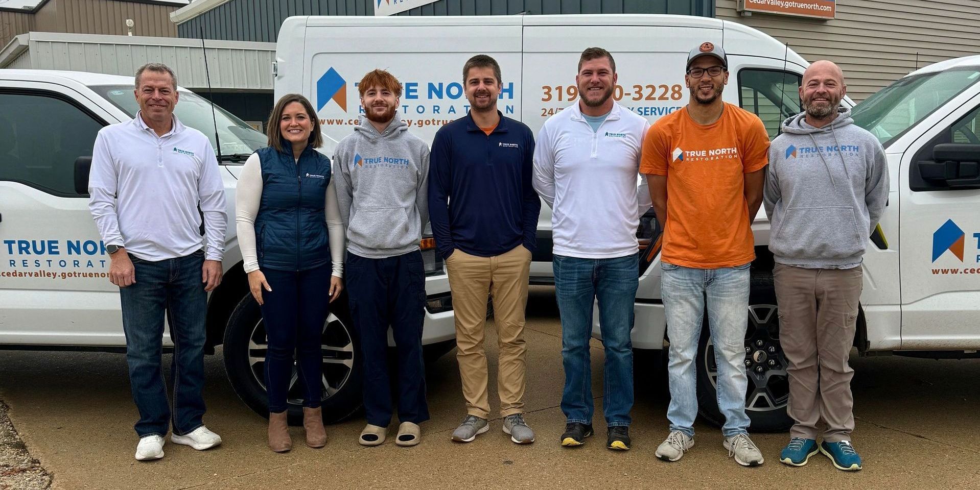 A group of people standing in front of a truck that says true north