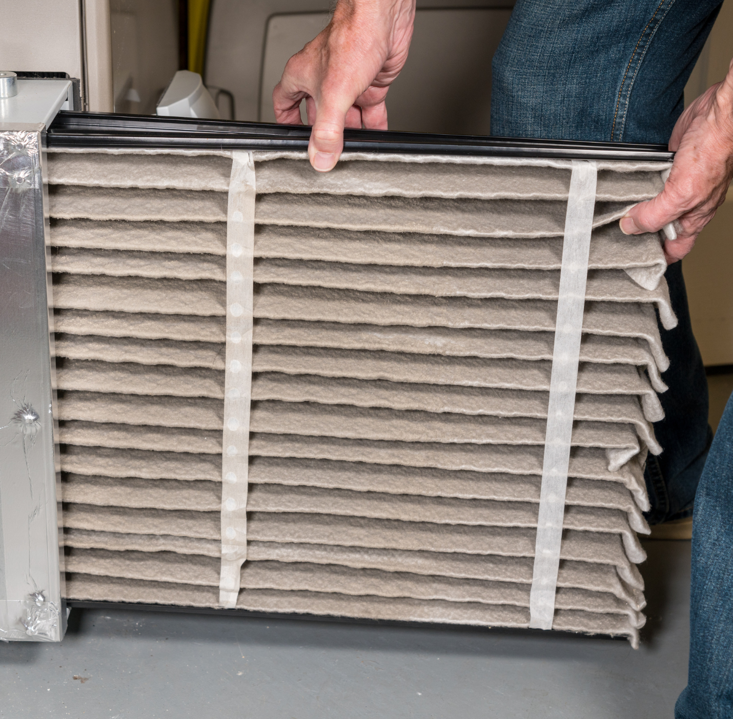 A person is holding a dirty air filter in their hands