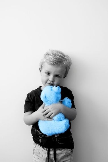 A young boy is holding a blue teddy bear