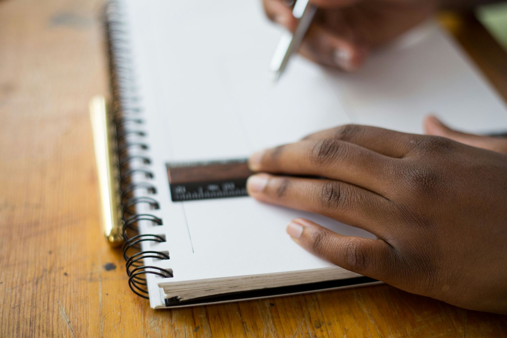 A person is writing in a notebook with a pen.