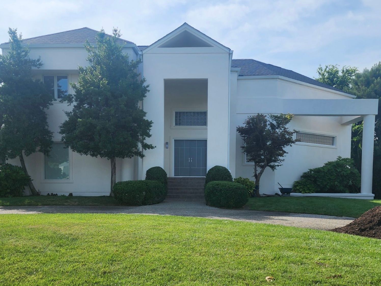 A large white house with a lush green lawn in front of it