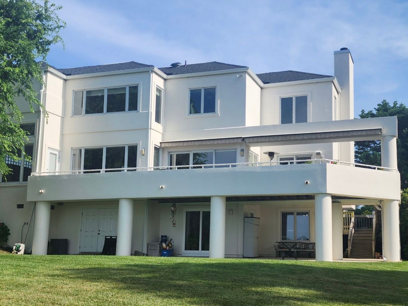 A large white house with a lot of windows is sitting on top of a lush green field.