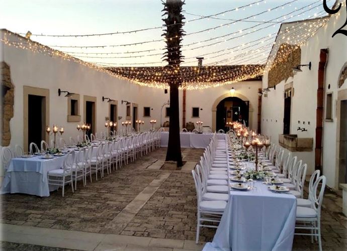 Tavoli rotondi con tovaglie bianche e bouquet di fiori all'esterno 