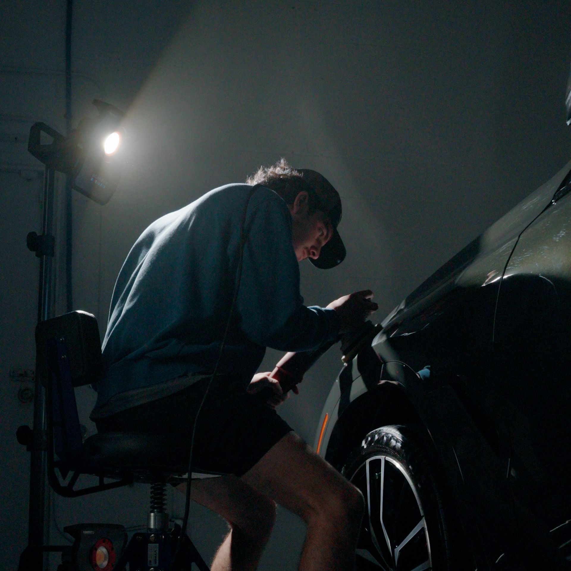 A man is sitting in a chair working on a car.
