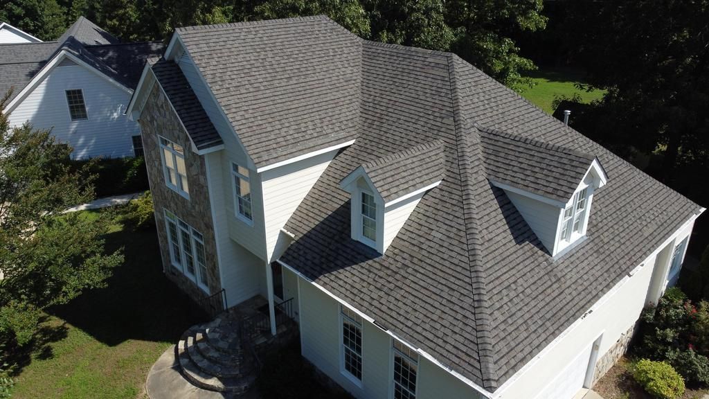 An aerial view of a large white house with a clean  gray roof.