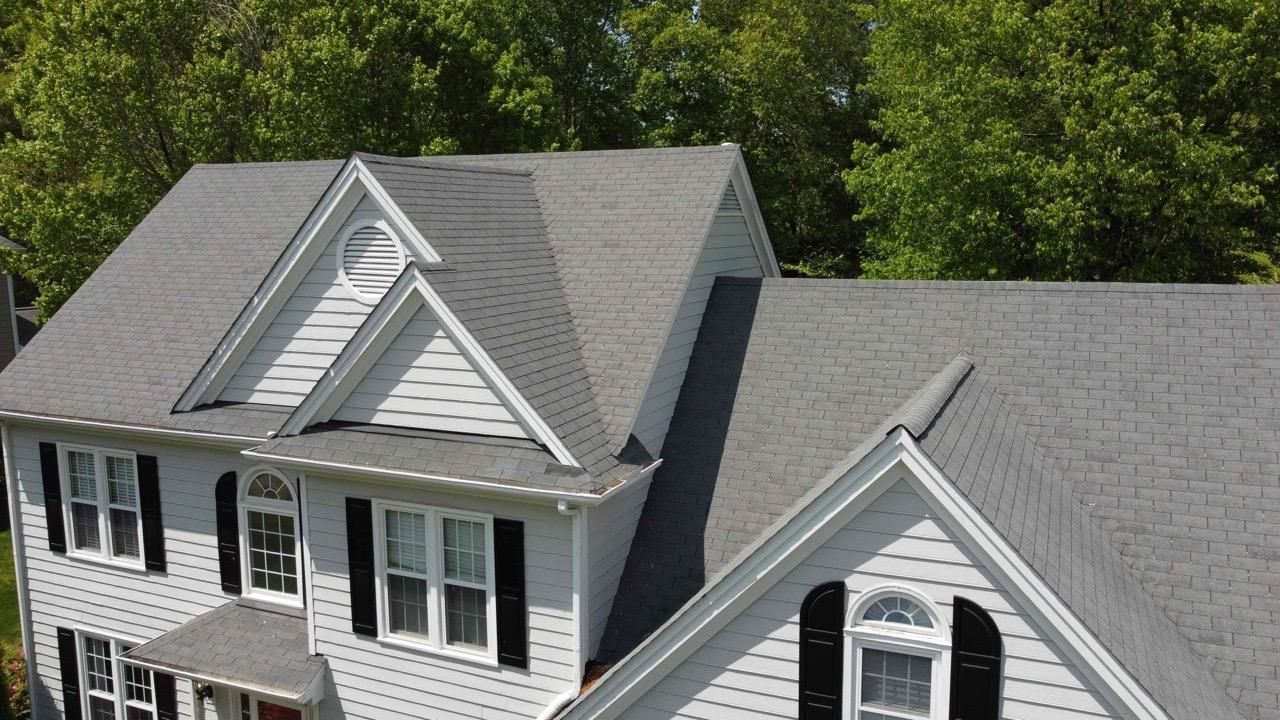 An aerial view of a white house with a gray roof and black shutters.