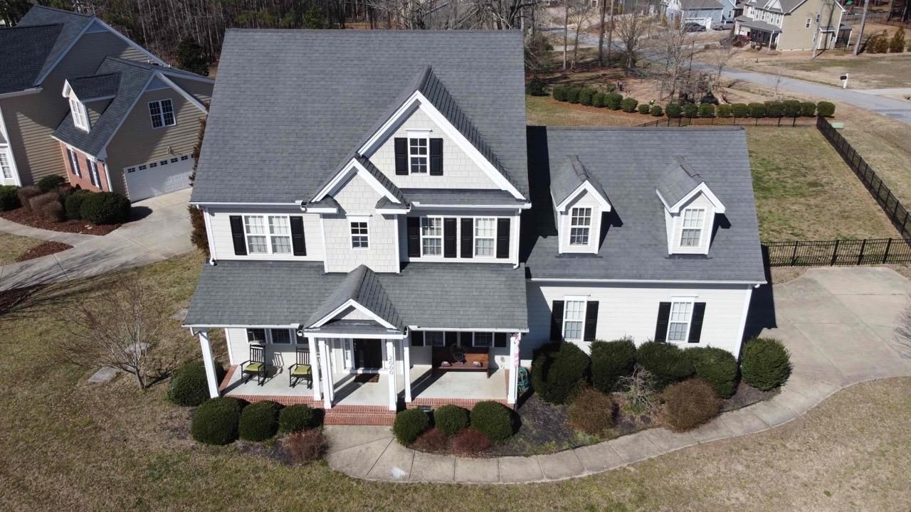 An aerial view of a large white house with a gray roof