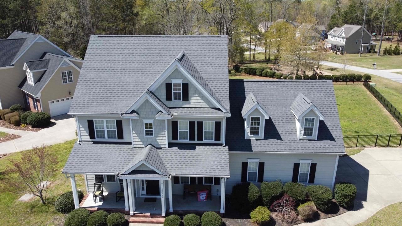 An aerial view of a large white house with a gray roof in a residential area.