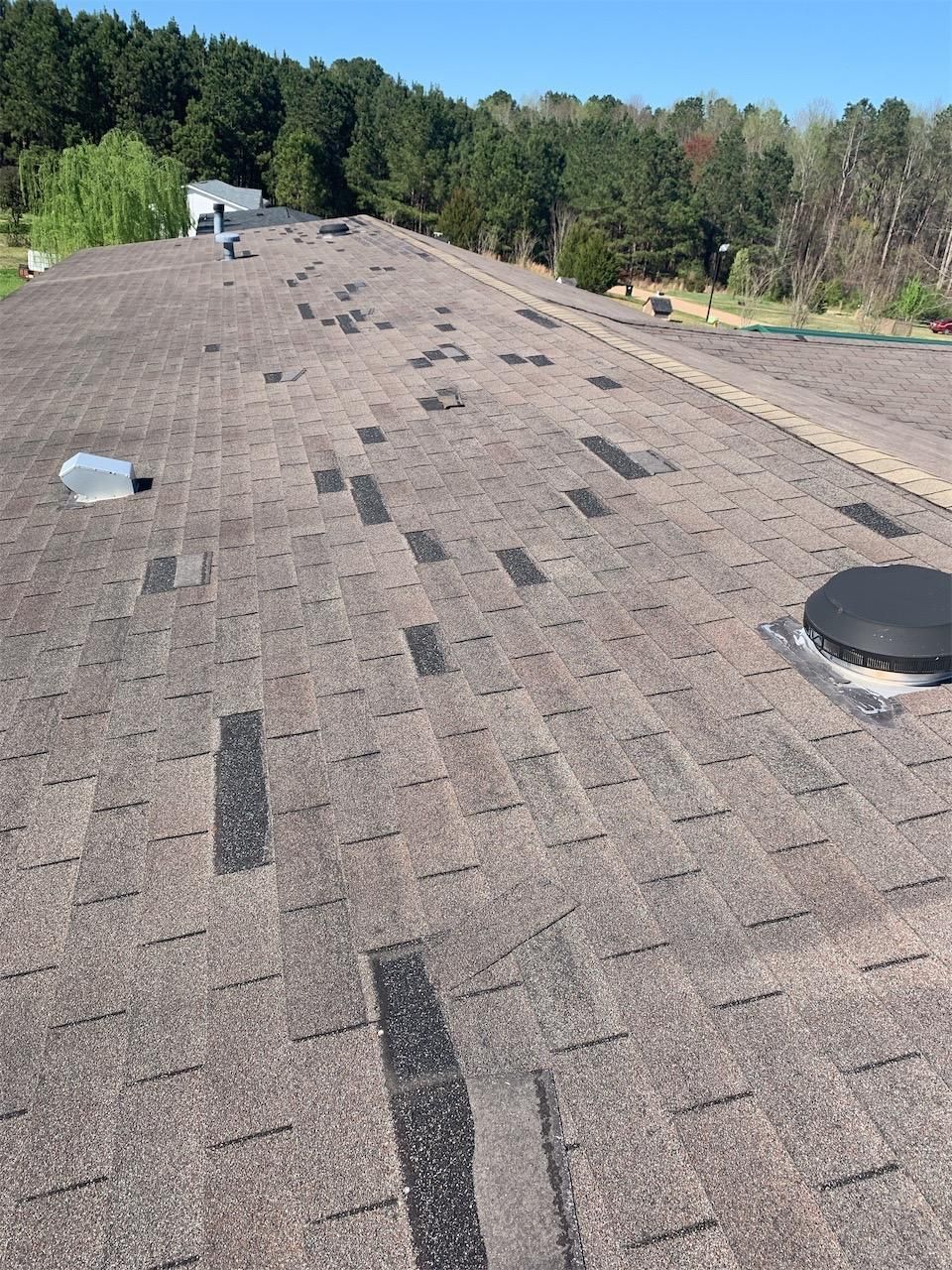 A roof with a lot of shingles on it and trees in the background.