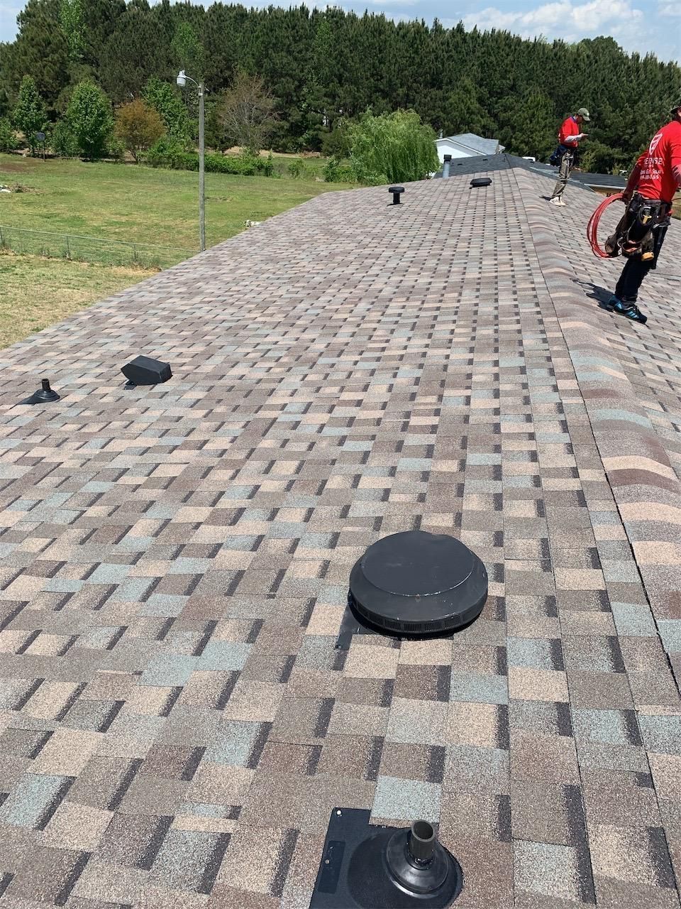 A clean roof with a lot of shingles and a person standing on it.