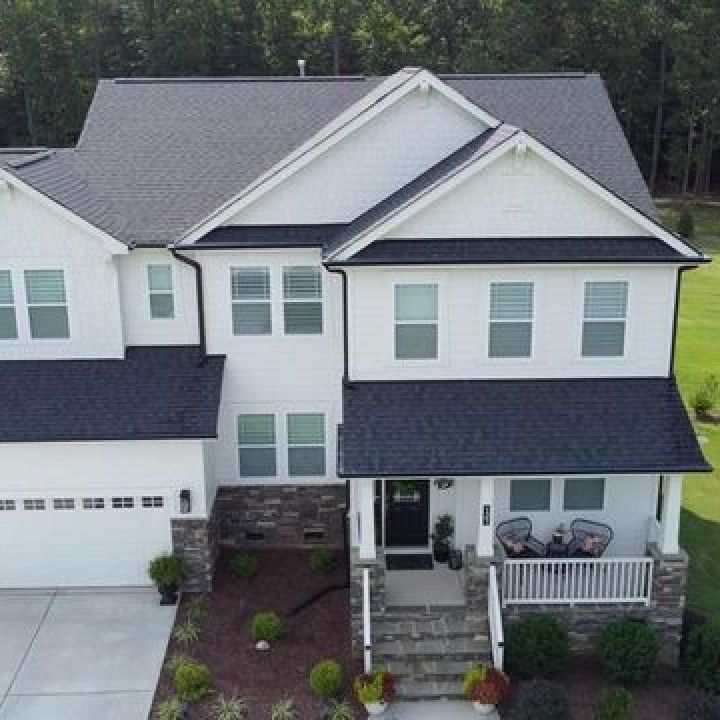 An aerial view of a large white house with a black roof
