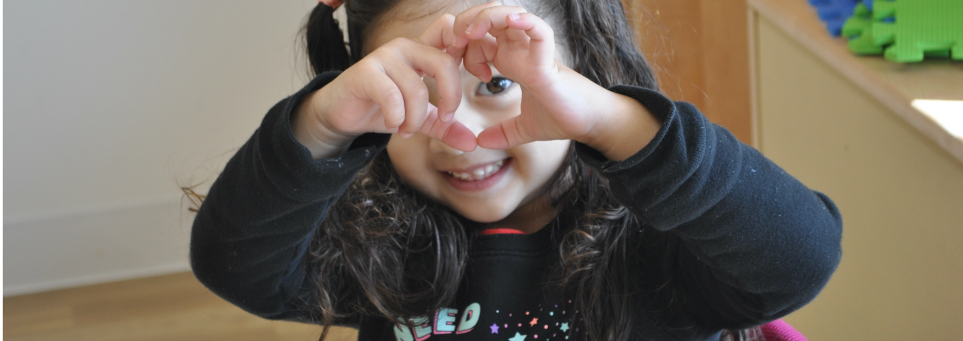 Little girl making the shape of a heart with her hands.