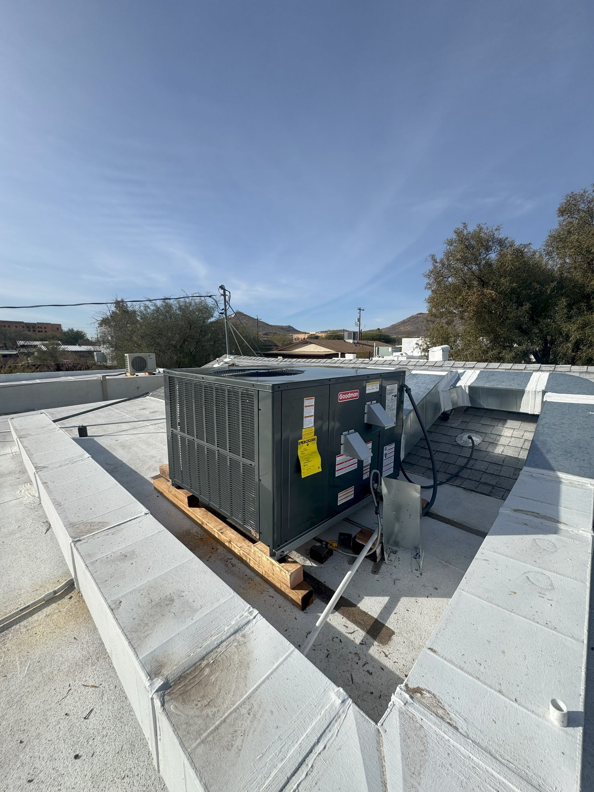 A large air conditioner is sitting on top of a concrete roof.