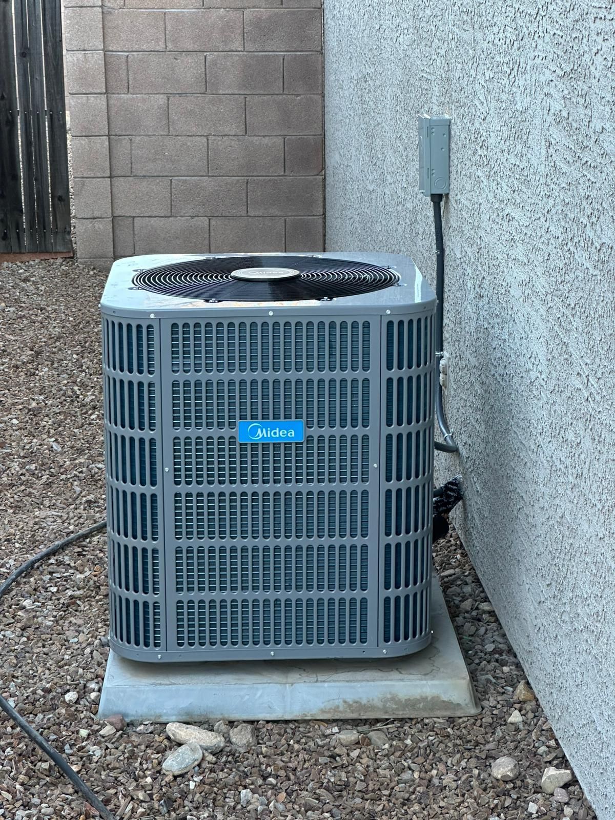 An air conditioner is sitting on a concrete platform next to a brick wall.