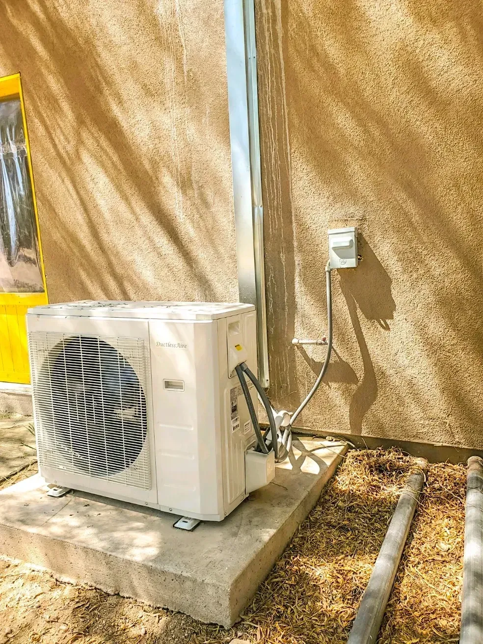 A white air conditioner is sitting on the side of a building.