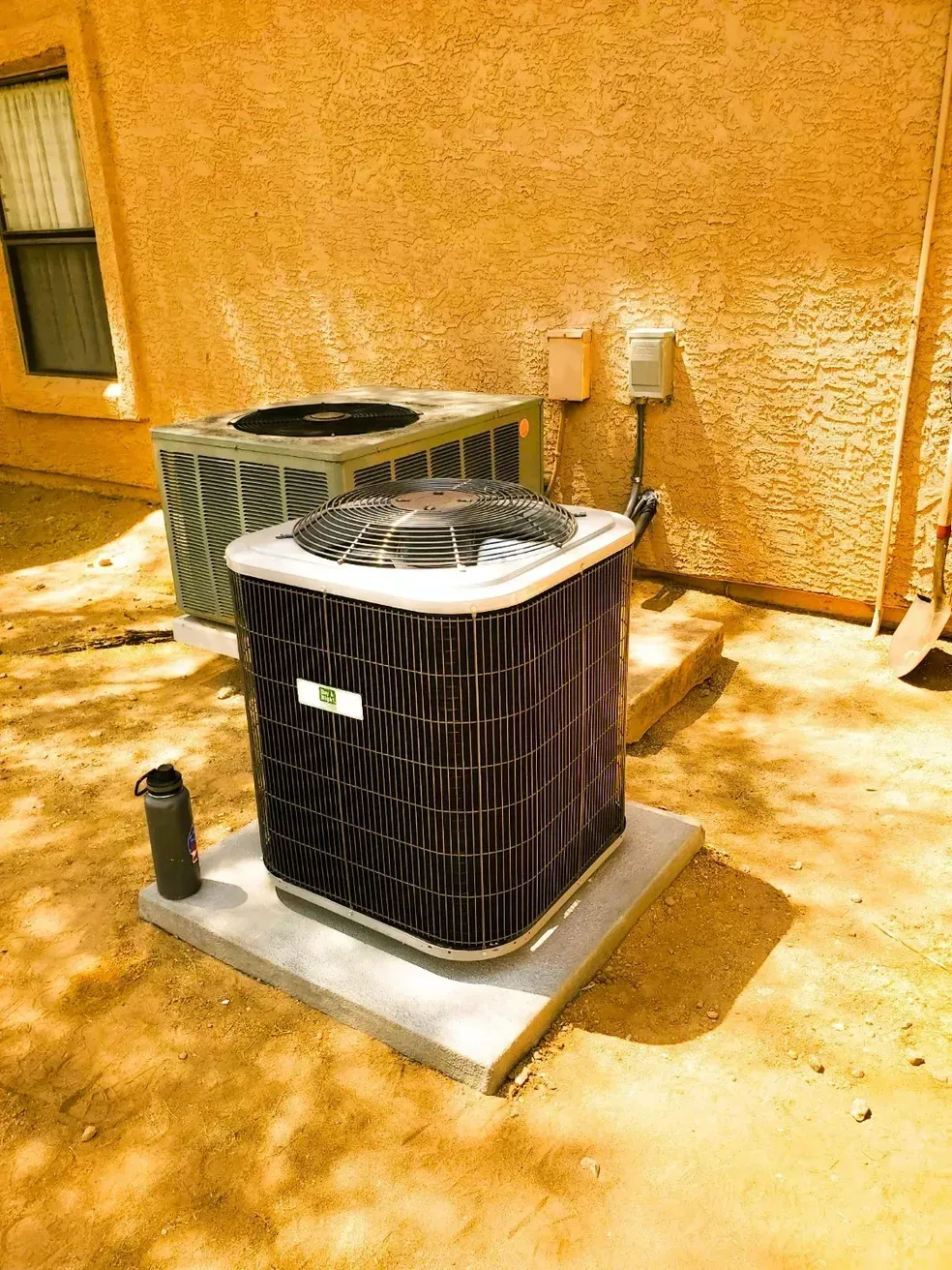 A couple of air conditioners are sitting outside of a house.