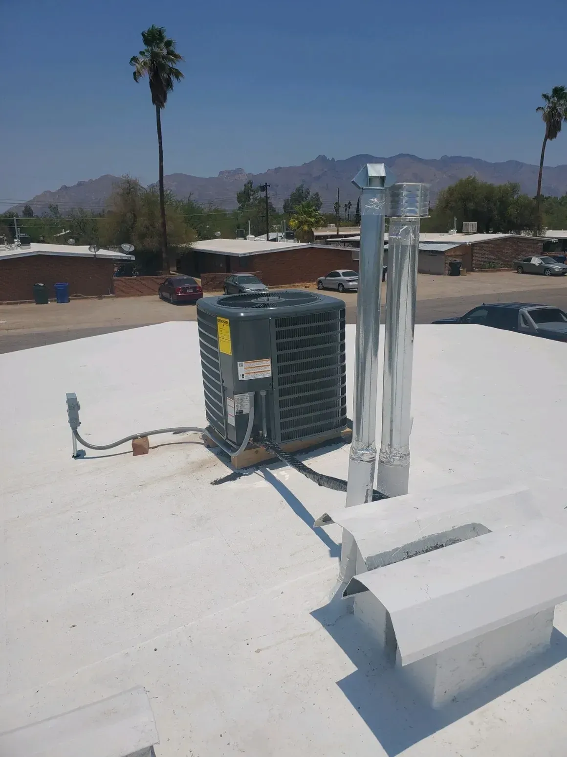 An air conditioner is sitting on top of a white roof.