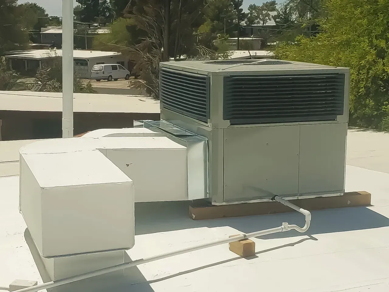 A large air conditioner is sitting on top of a white roof.