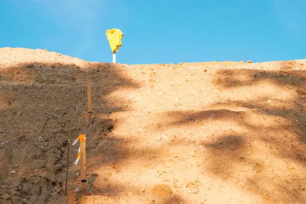 A Construction Site Slope Made of Light Brown Dirt With a Yellow Flag Marker — Copp & Co Civil Plant Hire in Proserpine, QLD