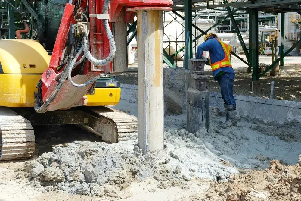 A Worker in a High-visibility Vest Stands Near a Heavy Construction Drill — Copp & Co Civil Plant Hire in Airlie Beach, QLD