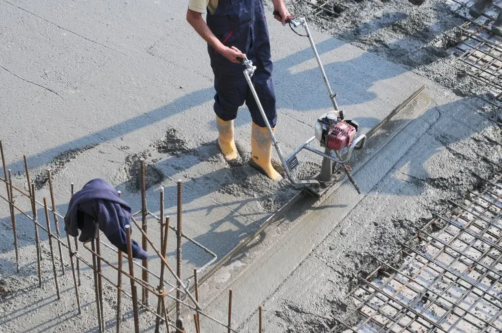 A Worker in Boots and Overalls Uses a Power Screed to Smooth — Copp & Co Civil Plant Hire in Airlie Beach, QLD