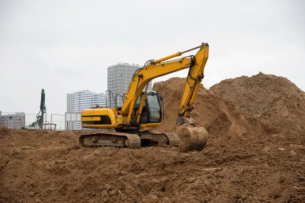 A Yellow Excavator Parked on a Large Pile of Dirt at a Construction Site — Copp & Co Civil Plant Hire in Cannonvale, QLD
