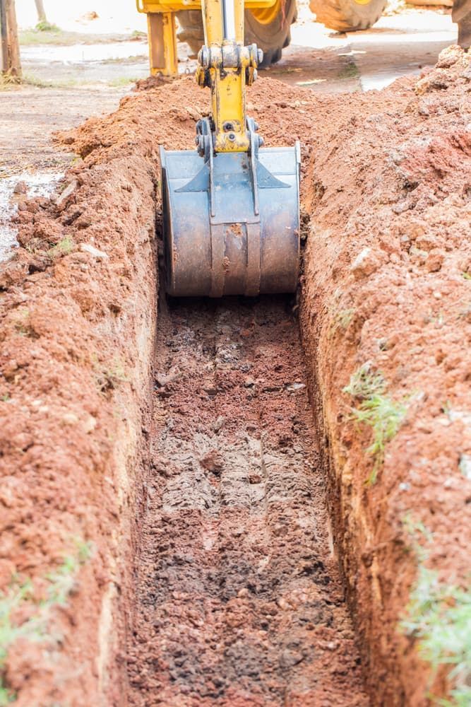 Yellow Excavator Bucket Digging a Deep, Narrow Trench in Red Dirt — Copp & Co Civil Plant Hire in Mount Julian, QLD