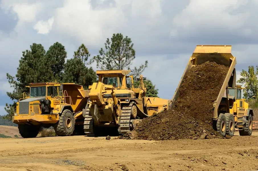 Two Yellow Dump Trucks and a Yellow Bulldozer on a Dirt Construction Site — Copp & Co Civil Plant Hire in Mount Julian, QLD