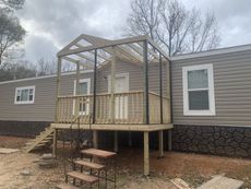 A mobile home with a screened in porch and stairs.