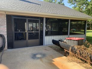 A house with a screened in porch and a hot tub in the backyard.